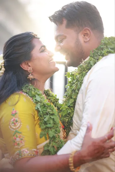 Bride and groom with ceremonial garlands in soft backlight
