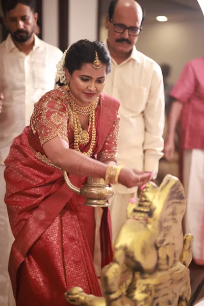 Bride in red silk at a ceremonial lamp