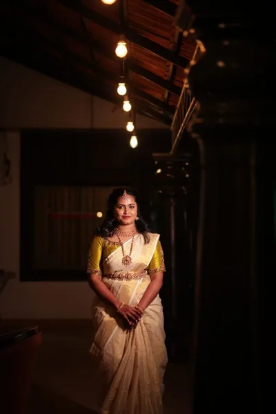 Kerala bride in ivory and gold on a carved wooden staircase