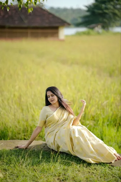 Ivory-and-gold set saree in a field beside a farmhouse